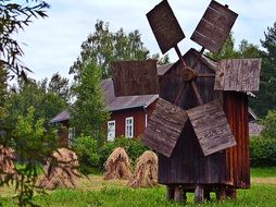 old wooden windmill, hay piles and village house, poland