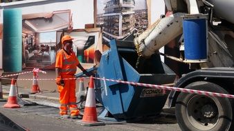 worker in overalls near a concrete mixer