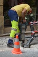 Worker with a drill performs roadworks