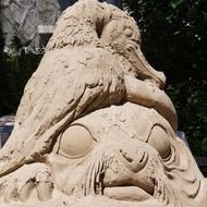 sculpture of a bird with big eyes from sand