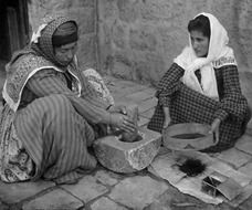 black and white photo of arab women chopping cereal coffee