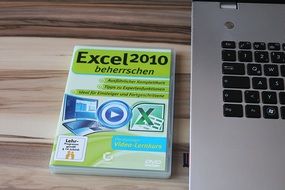 Book "Excel 2010" and a laptop on the table