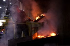 man with a shovel at work in aluminum factory