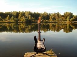 Standing electric guitar on a river bank