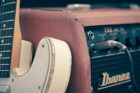 electric guitar stands near amplifier