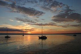 sailboats on the ocean at sunset