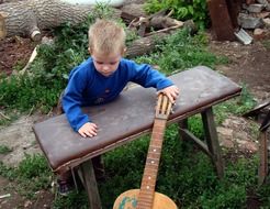 little boy touches a guitar