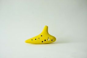 yellow ceramic ocarina on white surface