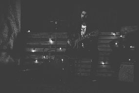 black and white photo of a musician with a guitar on stage