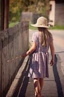 Child in a dress plays near a fence