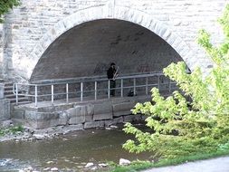 saxophonist by the river under the bridge