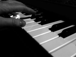 Black and white photo of the human playing on a piano