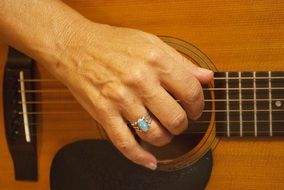 Hand with a ring on the guitar fretboard