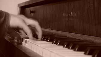 Hands on piano keys, black and white image