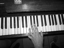 Black and white image of a hand on piano keys