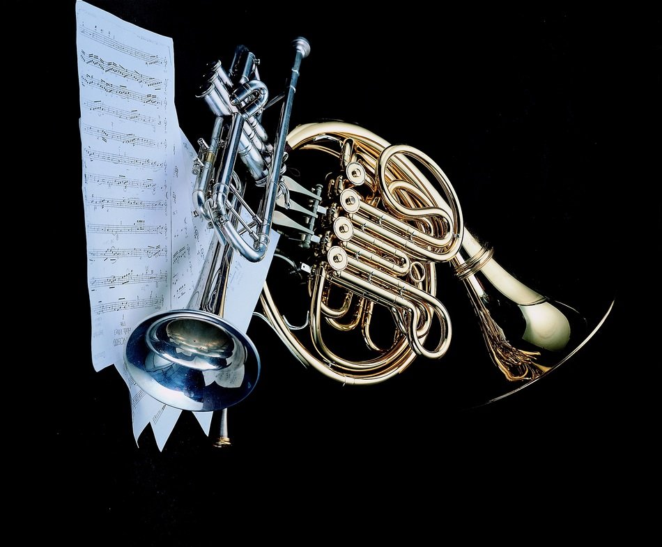 music sheet and two trumpets on black background
