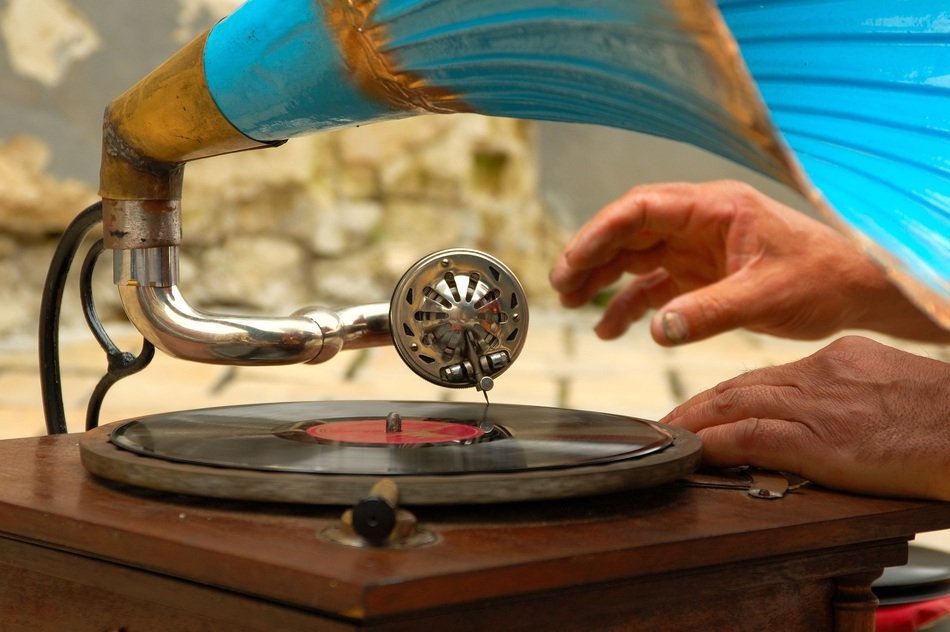 male hands at vintage gramophone playing vinyl disk