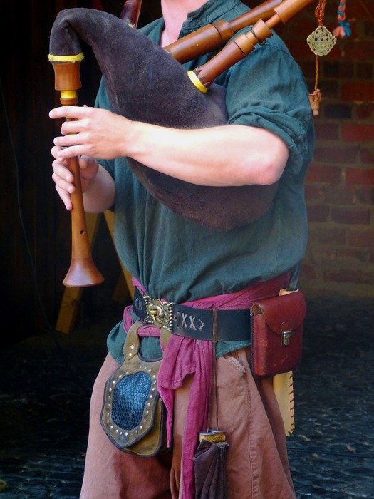 A man in colorful clothes plays the bagpipes