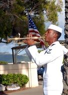 black trumpeter in white uniform playing outside
