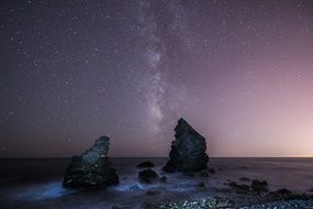 milky way boulders sea beach stars night