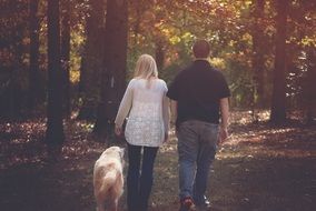 woman and boy walking with dog outdoors