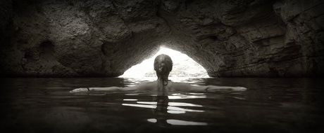 Black and white photo with back view of the girl floating in the grotto