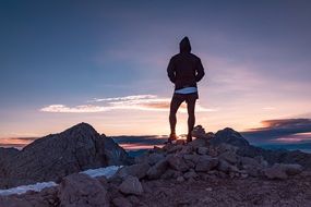 Man on mountain top looking at sunrise