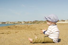 sitting little boy on the sand by the sea