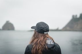 girl in a cap on the shore of the reservoir