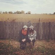 two friends sit by the fence in the village