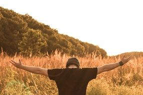 a man with his arms outstretched in a meadow