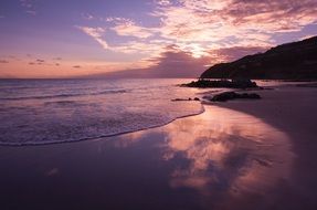 pink sunset reflected in the surf on the beach