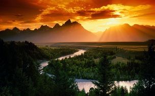 landscape of orange sky over the green forest and mountains