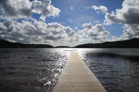 boardwalk on water beneath cloudy sky