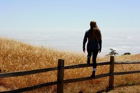 girl standing on fence lookout sea view