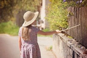 Girl in a hat near a wooden fence