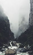 stormy stream in a gorge on a background of fog