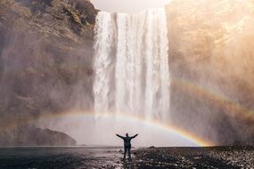 Man on shore waterfall rainbow view