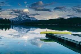 boat canoe on pier on the beautiful landscape with the snowy mountains on horizon