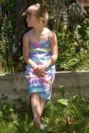 girl in a striped dress sitting in the summer garden
