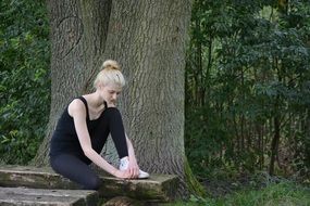 slim girl sitting near the trees