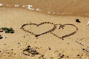 two hearts drawing on sand at water