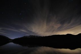 night landscape of mountains and their reflection in the lake on a background of clouds