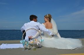 wedding couple sit on beach in front of sea