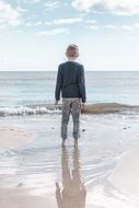 back view of the child is in the water on the shore