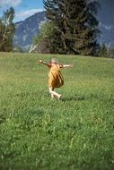 the child runs through a green meadow