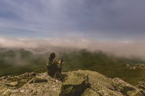 woman and dog sitting on top of a mountain