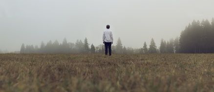 lonely man on a field against a background of trees