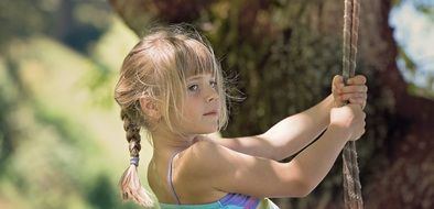 Little girl with a scythe on a swing