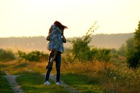 a loving pair kissing on the footpath leading to the forest